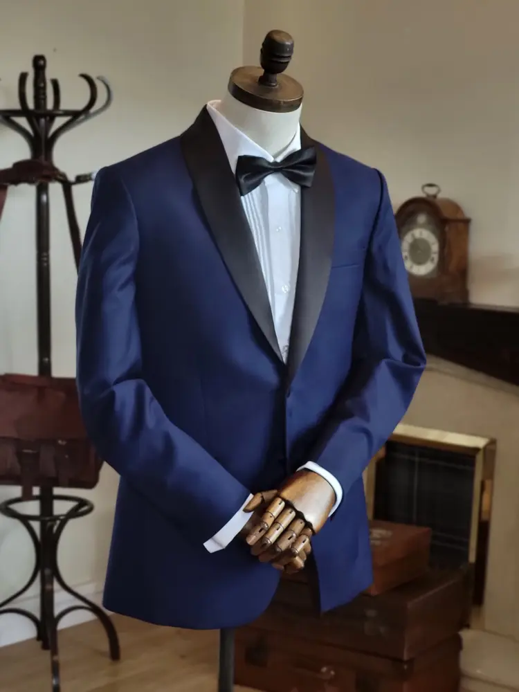 Navy tuxedo jacket with black satin shawl lapel and bow tie on a tailor's mannequin