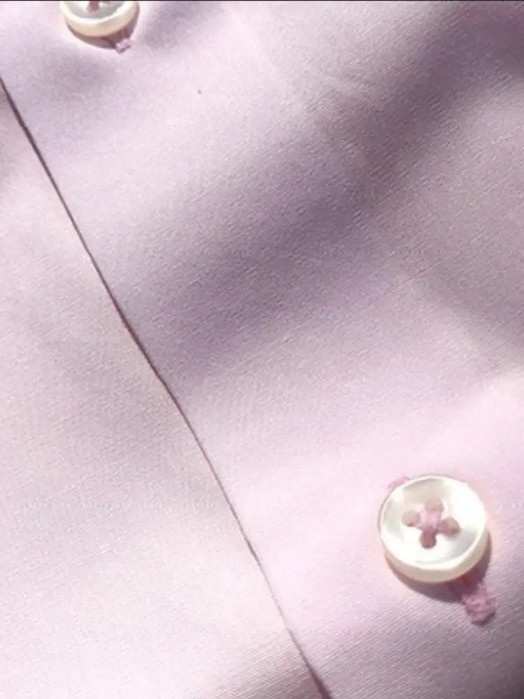 Close-up of a pale pink handmade shirt placket with mother-of-pearl buttons